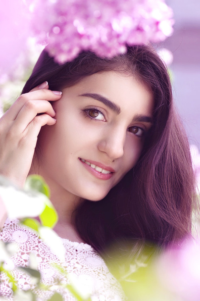 Beautiful young woman in spring lilac garden - Фото, зображення