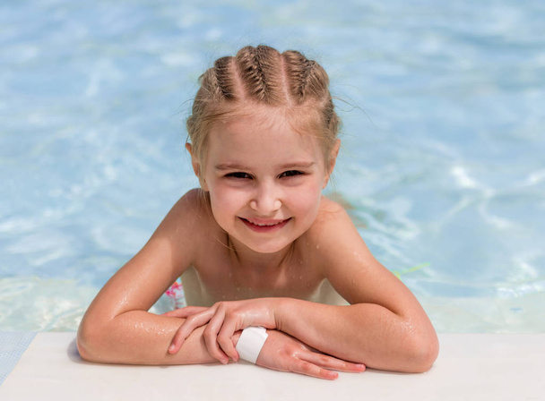 Smiling girl swim to the poolside - Foto, afbeelding
