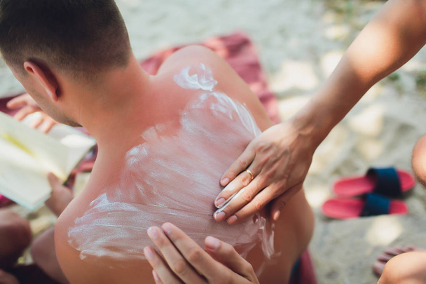 Man on the beach gets a boyfriend back on sunscreen. - Фото, зображення