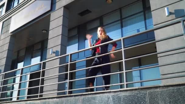 beautiful blonde woman dancing near metal railings on city street - Кадры, видео