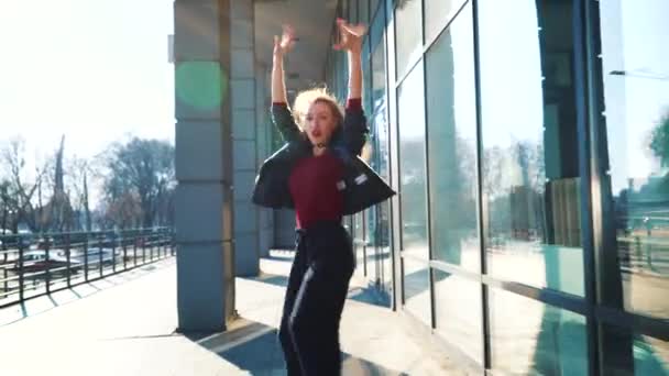 blonde female street dancer performing in sun light near modern building - Кадри, відео