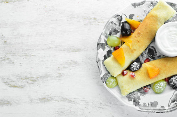 Pancakes with fruit and sour cream. Dessert. On a wooden background. Top view. Free space for your text. - Foto, imagen