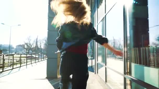 pretty blonde woman performing contemporary dance in sunny urban environment - Filmati, video