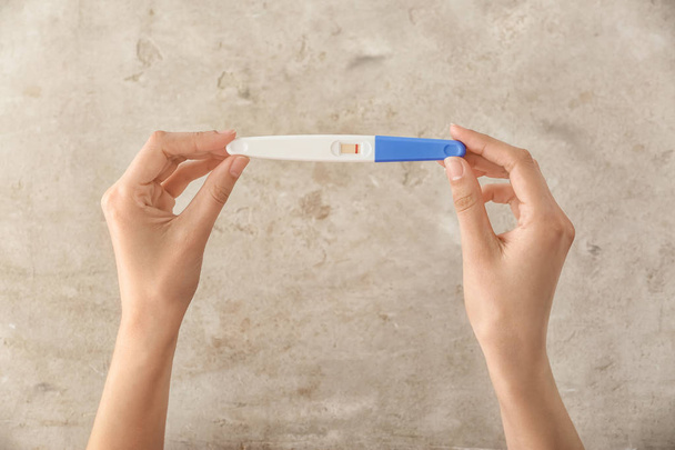 Female hands with pregnancy test on grey background - Fotoğraf, Görsel