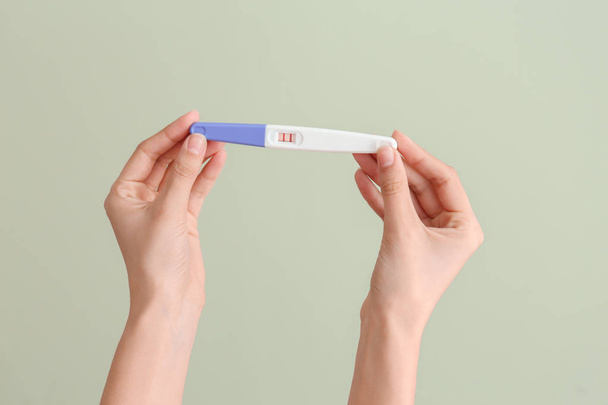 色の背景に妊娠テストを持つ女性の手 - 写真・画像