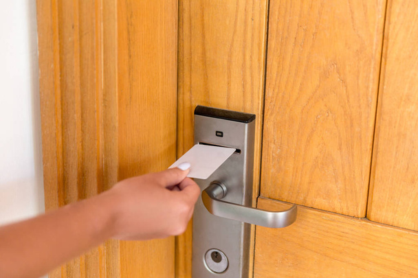 Γυναικείο χέρι με κάρτα-κλειδί στην ηλεκτρονική κλειδαριά. γυναικεία κάρτα κλειδί χειρός και ανοιχτή ηλεκτρονική πόρτα κλειδώματος - Φωτογραφία, εικόνα