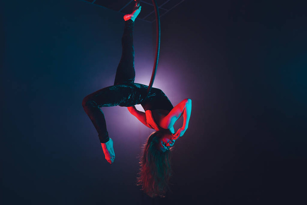 Aerial acrobat in the ring. A young girl performs the acrobatic elements in the air ring. - Foto, afbeelding