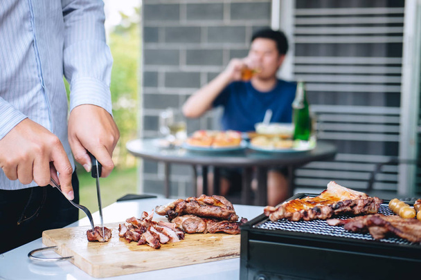 Group of friends Two young man enjoying grilled meat and raise a - Foto, Imagem