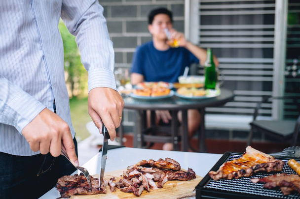 Group of friends Two young man enjoying grilled meat and raise a - Photo, Image