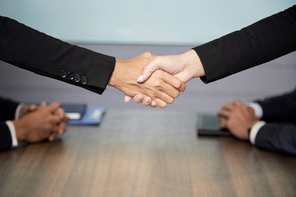 Вид збоку бізнесменів у костюмах тремтять руки під час зустрічі на конференції
 - Фото, зображення