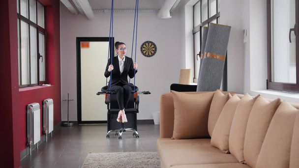 Business concept. A woman in the business centre on the swings - Foto, Imagen