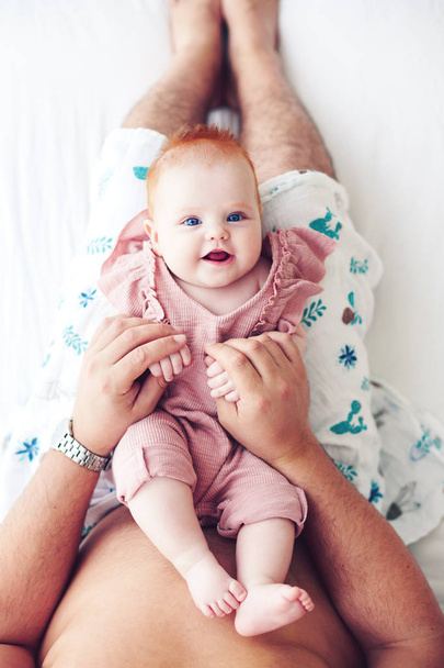 top view of father playing with cute infant baby daughter in bed, at home - Foto, afbeelding