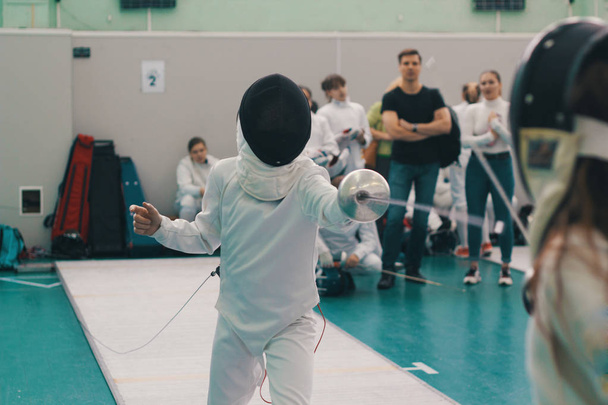 A girl fencer having fencing duel on tournament. A girl holding a saber - Foto, immagini