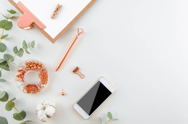 Flat lay beautiful Stylish workspace. Fashion women blogger workspace with a smartphone, cotton flowers, eucalyptus branches and rose gold office supplies top view background. - Valokuva, kuva
