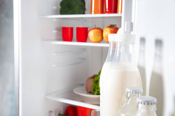 Пляшки молока у відкритому холодильнику
 - Фото, зображення
