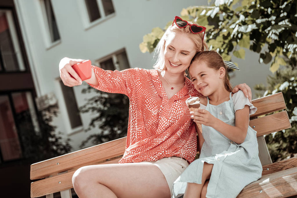 Delighted positive woman taking a selfie with her daughter - Fotoğraf, Görsel