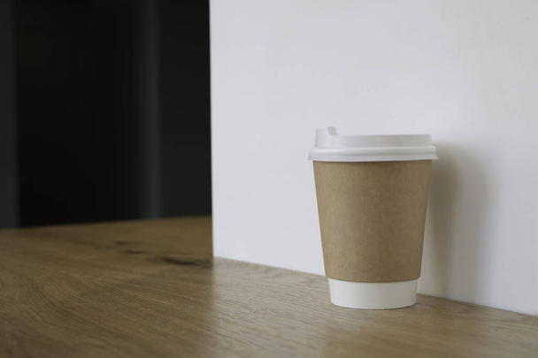 Gúnyolódni egy csésze kávét. Egy pohár van az asztalon egy kávézóban, kávé eladása a háttérben. Kávé-hoz megy. Világos falak. Fából készült asztal. Cafe.  - Fotó, kép