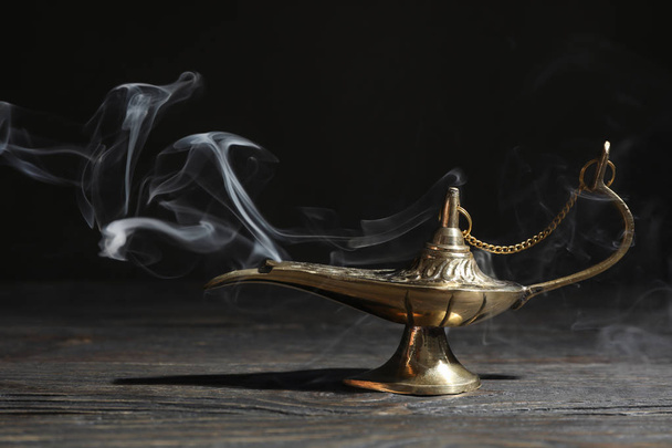 Lámpara mágica Aladdin sobre mesa de madera sobre fondo oscuro
 - Foto, imagen