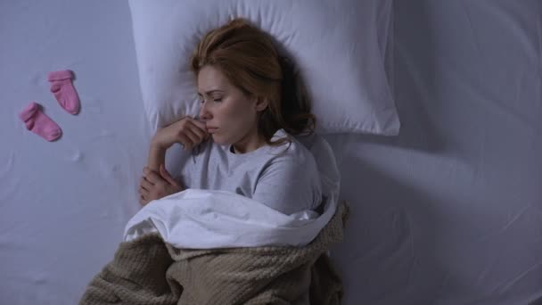 Lady crying hiding little baby socks under pillow, miscarriage, infertility - Video, Çekim