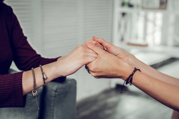 Supportive psychologist wearing bracelets shaking hands of client - Φωτογραφία, εικόνα
