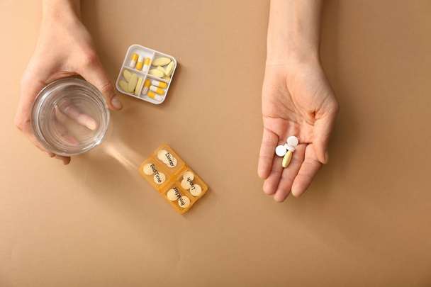 Female hands with pills and glass of water on color background - Фото, зображення