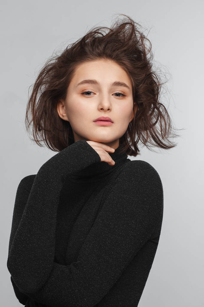 Portrait of a beautiful teen girl in a black sweater on a gray background. Combed up hair - Foto, immagini
