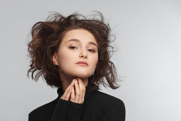 Portrait of a beautiful teen girl in a black sweater on a gray background. Combed up hair - Foto, imagen