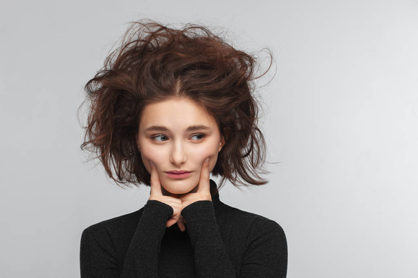 Portrait of a beautiful teen girl in a black sweater on a gray background. Combed up hair - Foto, afbeelding