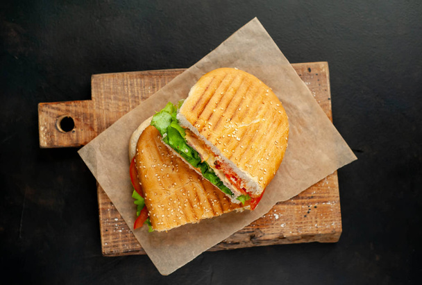 Grilled panini sandwich on wooden chopping board on stone background - Photo, Image