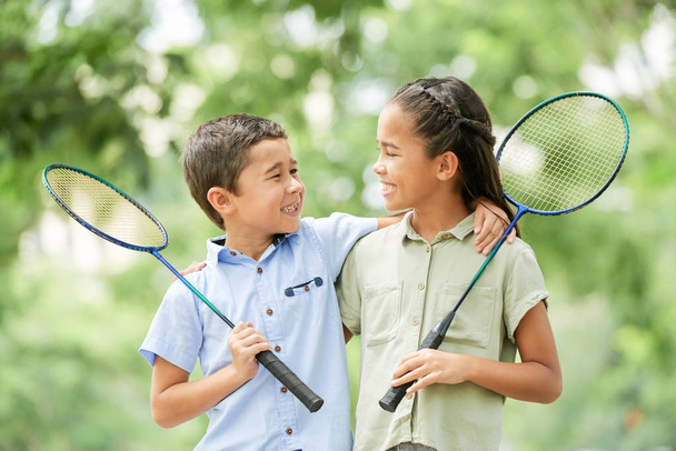 Allegro fratello e sorella con racchette badminton che si abbracciano e si guardano
 - Foto, immagini