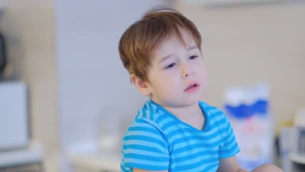 surullinen kasvot poika kolme vuotta vanha, istuu keittiössä kotona ja puhuu kameraan
 - Materiaali, video