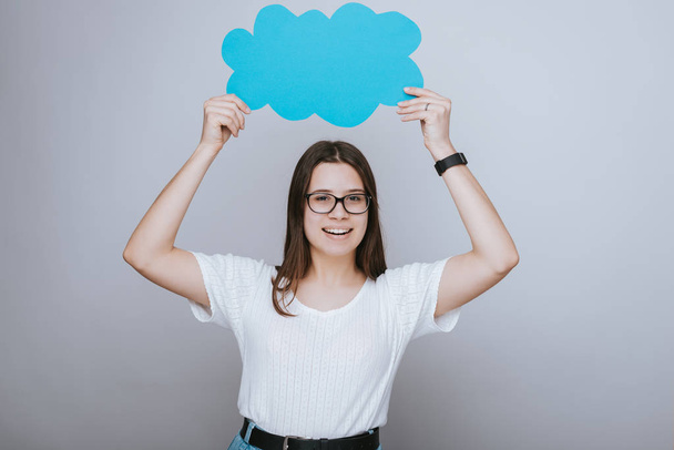 Cheerful young woman holding blue speech cloud over head  - Photo, Image