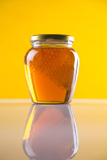 Honey in jar with honey dipper on wooden background - Photo, image