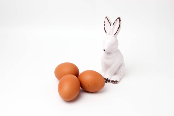 easter bunny ceramic figurine three eggs on white background - 写真・画像