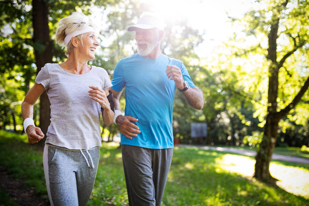 Senior couple jogging and running outdoors in park nature - Photo, Image