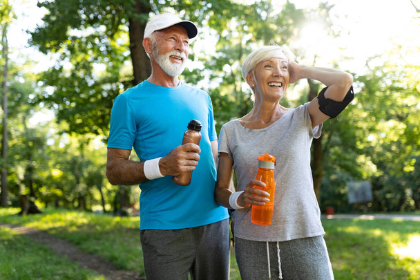Happy fit senior couple exercising in outdoor park - Foto, afbeelding