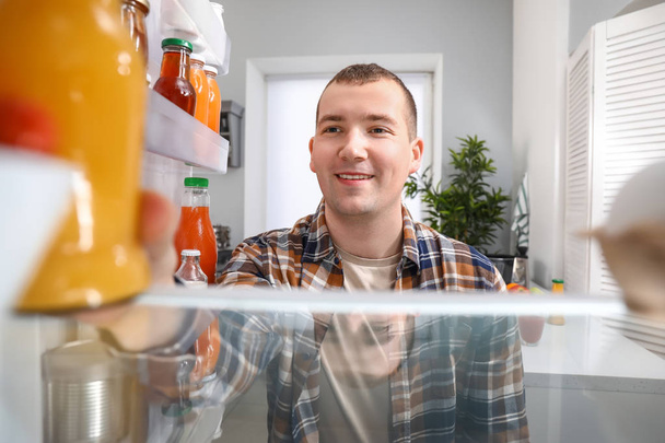 Homme sortant de la nourriture du réfrigérateur à la maison, vue de l'intérieur
 - Photo, image