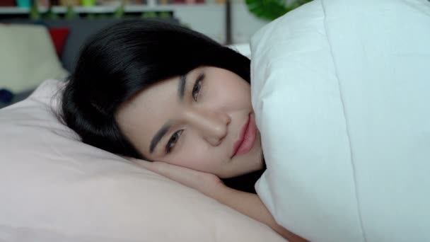 hübsche junge asiatische Frau schläft im gemütlichen Bett und träumt. glückliche und attraktive Frau wacht auf, öffnet ihre schönen Augen, lächelt und freut sich auf einen wunderbaren Tag - Filmmaterial, Video