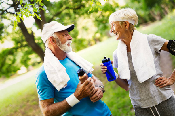 Senior couple jogging and running outdoors in nature - Фото, зображення