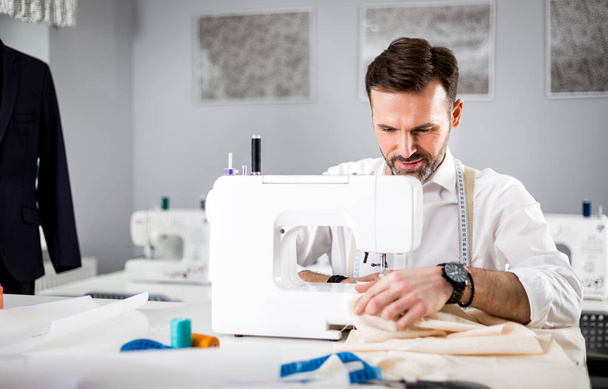 Tailor working with sewing machine at fashion design workshop - Фото, зображення