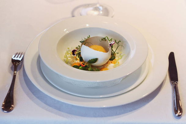 restaurant dish served on a white tablecloth. foie gras with lettuce in eggshell - Fotó, kép