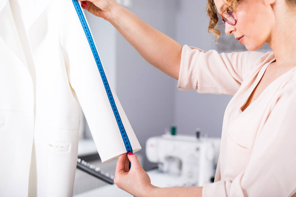 Tailor measuring lady jacket on mannequin at fashion design workshop - Foto, Imagem