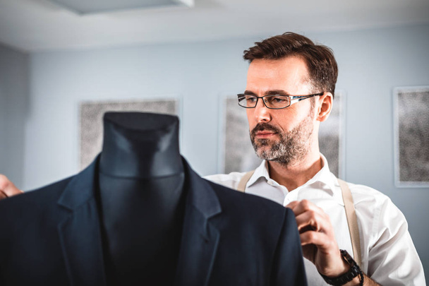 Tailor measuring jacket suit on mannequin at fashion design workshop - Фото, зображення