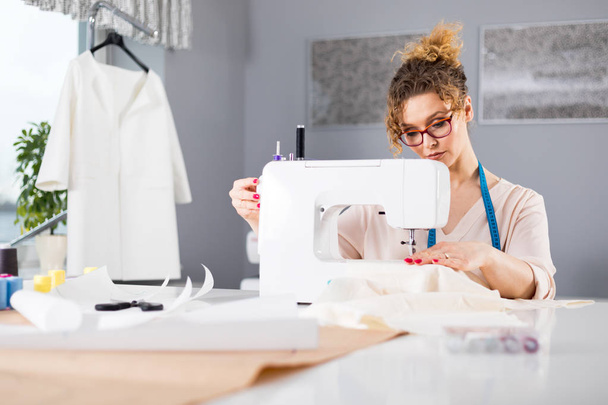 Tailor during work using sewing machine, fashion designer at workshop - Φωτογραφία, εικόνα