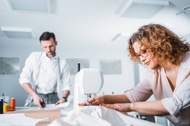 Professional tailors during work on project in fashion design studio, using sewing equipment - Fotografie, Obrázek