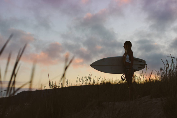 Beautiful surfer holding her surfboard in the morning at the bea - Foto, Imagen