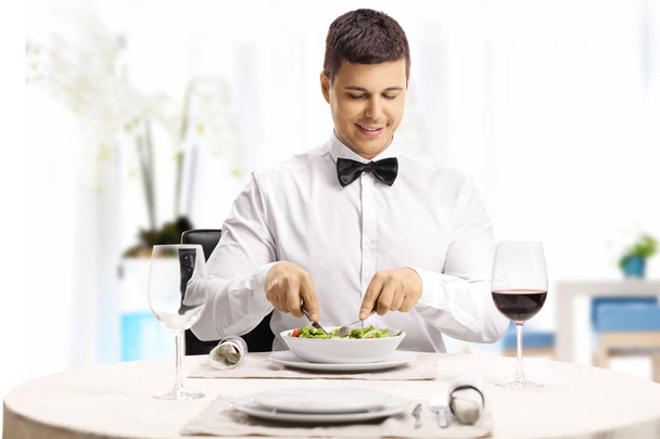 Young handsome man eating a salad at a modern fancy restaurant  - Photo, Image