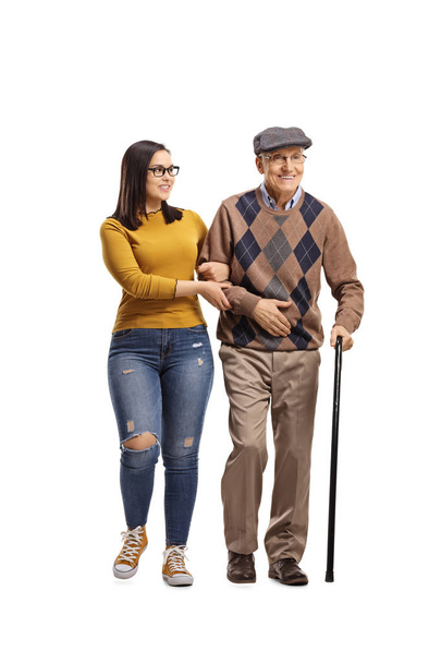 Full length portrait of a young female helping a senior man walking with a cane isolated on white background - Фото, зображення