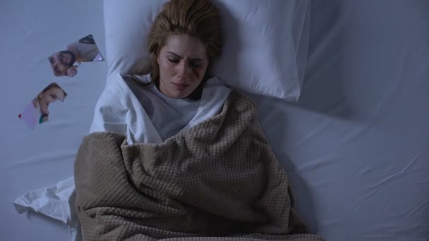 Plačící žena s poraněný tváří ležící v posteli, roztržená fotka u polštáře, rozchod - Záběry, video