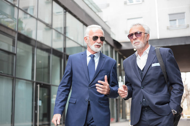 Deux hommes d'affaires seniors marchant dans la rue, discutant
 - Photo, image
